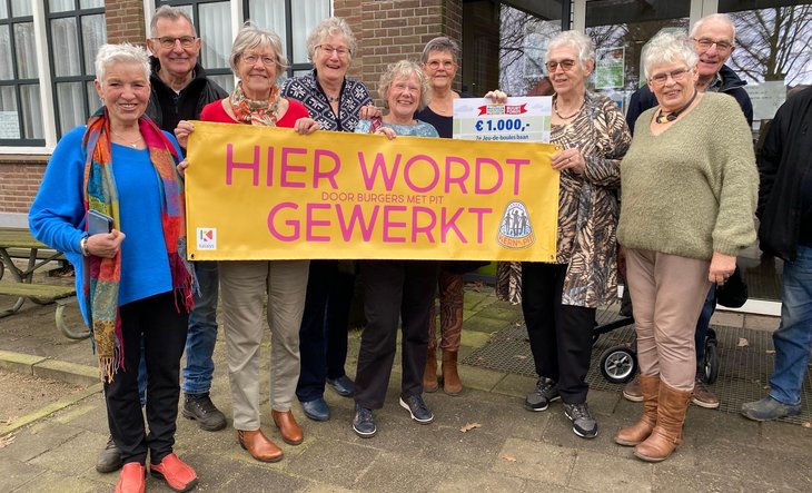 Groep mensen met spandoek met tekst 'Hier wordt gewerkt'