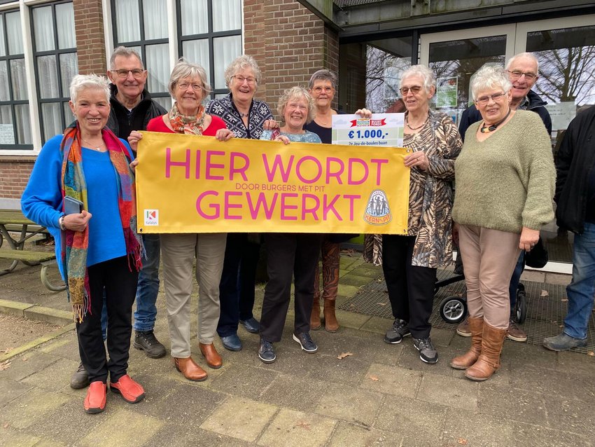 Groep mensen met spandoek met tekst 'Hier wordt gewerkt'